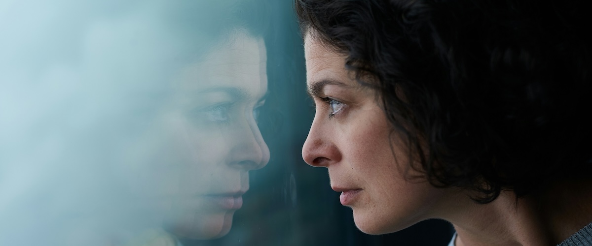 A woman sitting quietly, looking thoughtful and a little overwhelmed